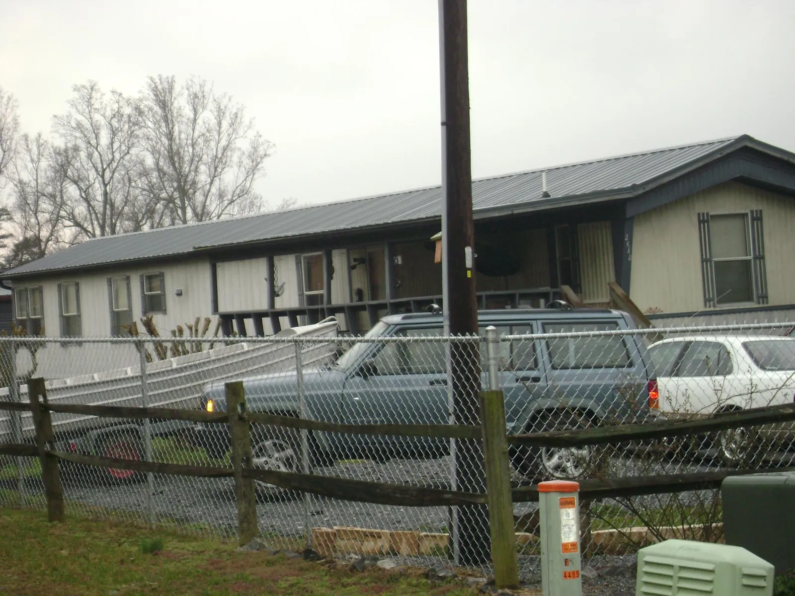 Dark metal roof on a long single story building behind a chain link fence in Saint Francis