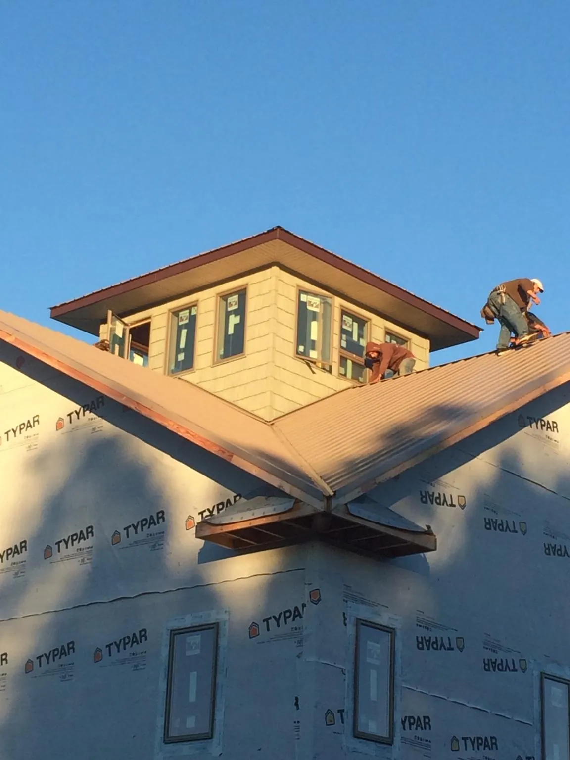 Roofers working around a rooftop cupola on a new metal roof at sunset — Roof Waterproofing in Saint Francis by Roofing Brothers